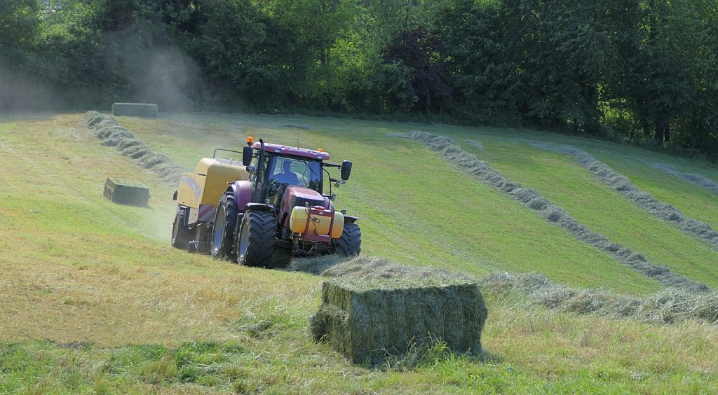 Tractor working in a field baling hay.