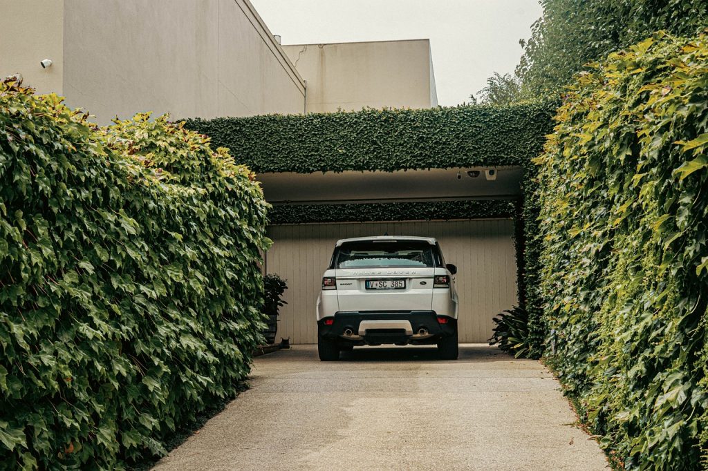 A Range Rover parked on a drive hedged in on all sides to protect privacy.