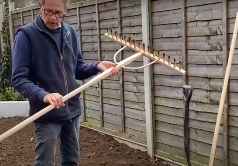 Ken holds a rake and gets ready for turf in a new garden.