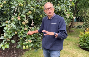 Ken by an apple tree with his jobs for the garden in July.