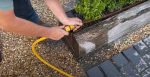 A hand connecting up a hosepipe to an outdoor watering systems.